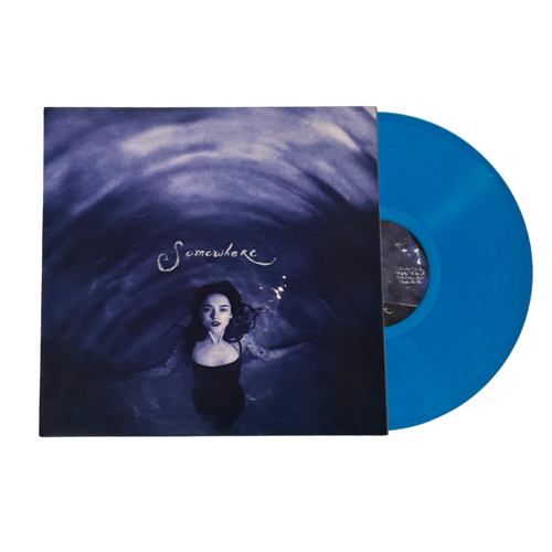 A vinyl record partially pulled from its sleeve, showing a bright translucent blue disc alongside the album cover art featuring a woman in water with the title 'Somewhere' in script.
