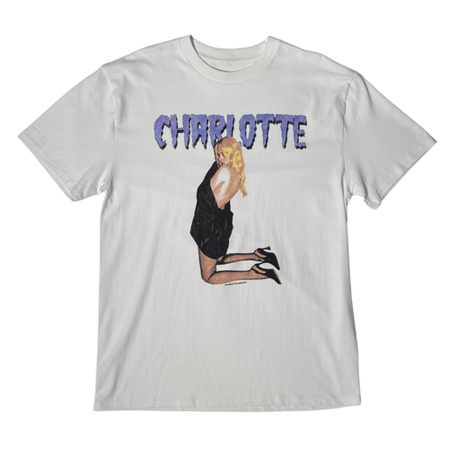 A light gray short-sleeve t-shirt featuring a graphic print of a blonde woman in a black dress kneeling, with the word 'CHARLOTTE' printed above in a textured purple font.