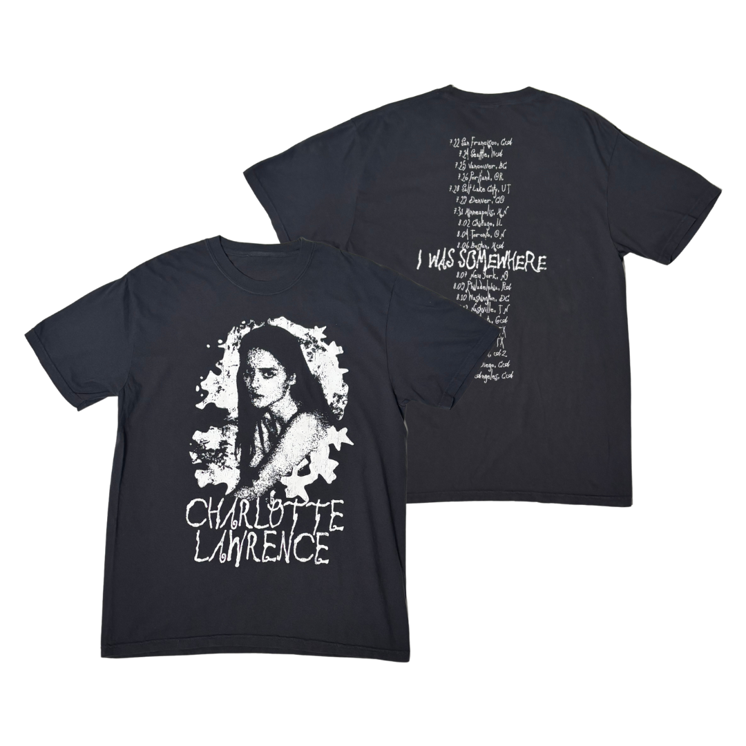 A black short-sleeve graphic T-shirt shown from both front and back on a plain white background. The front features a large white portrait graphic of a woman with the text 'CHARLOTTE LAWRENCE' below.